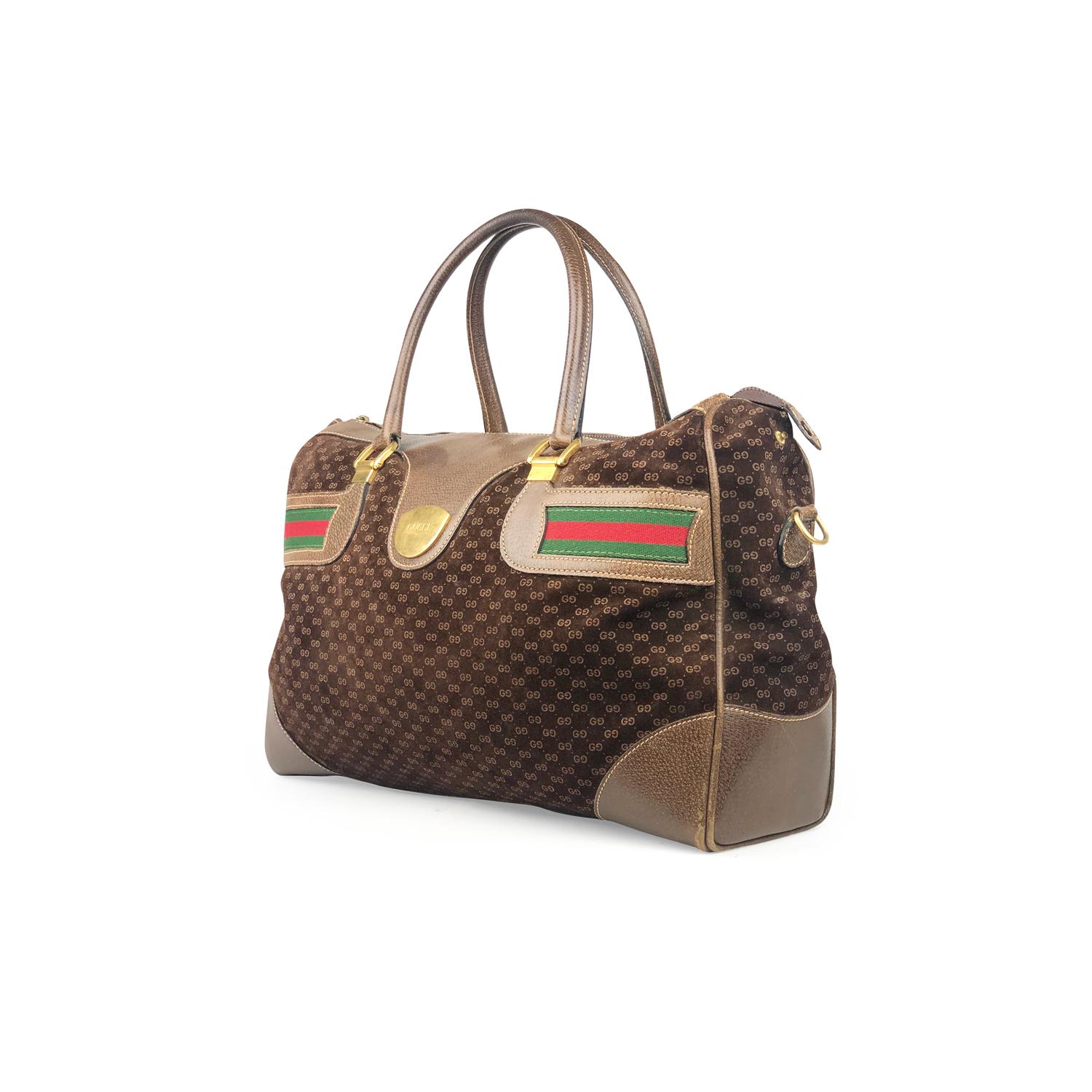 Brown GG suede Gucci duffle bag with

- Gold-tone hardware
- Brown leather trim
- Dual rolled leather top handles
- Red and green Web canvas accents
- Protective feet at base, natural canvas lining, single pocket at interior wall with zip closure