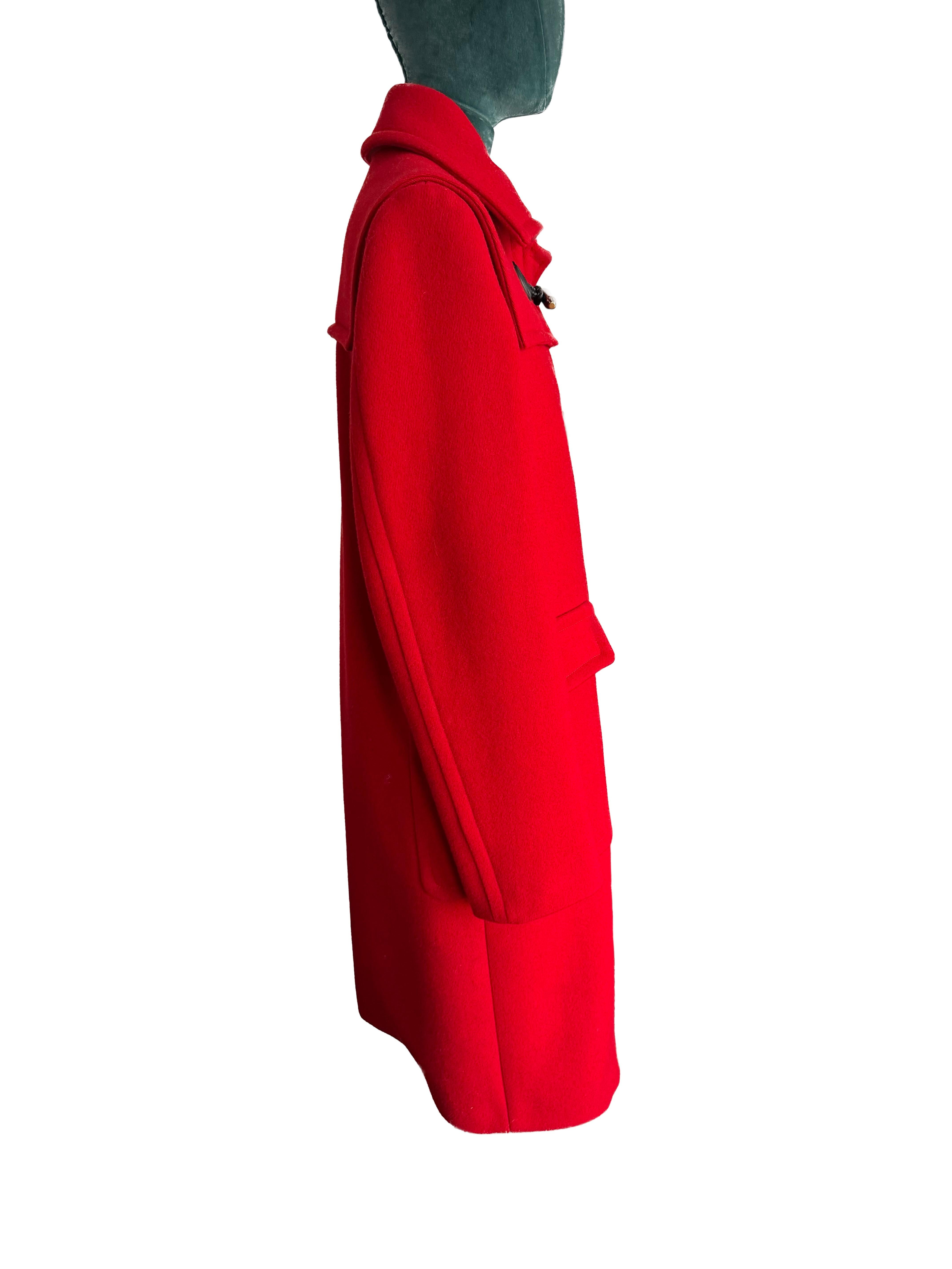 Betreten Sie mit dem exquisiten Gucci Red Ruffle Duffle Coat ein Reich von dauerhaftem Stil und raffiniertem Luxus. Dieses zeitlose Stück geht über die Mode hinaus und verkörpert die Essenz von Raffinesse und sorgfältiger Handwerkskunst. Der Mantel