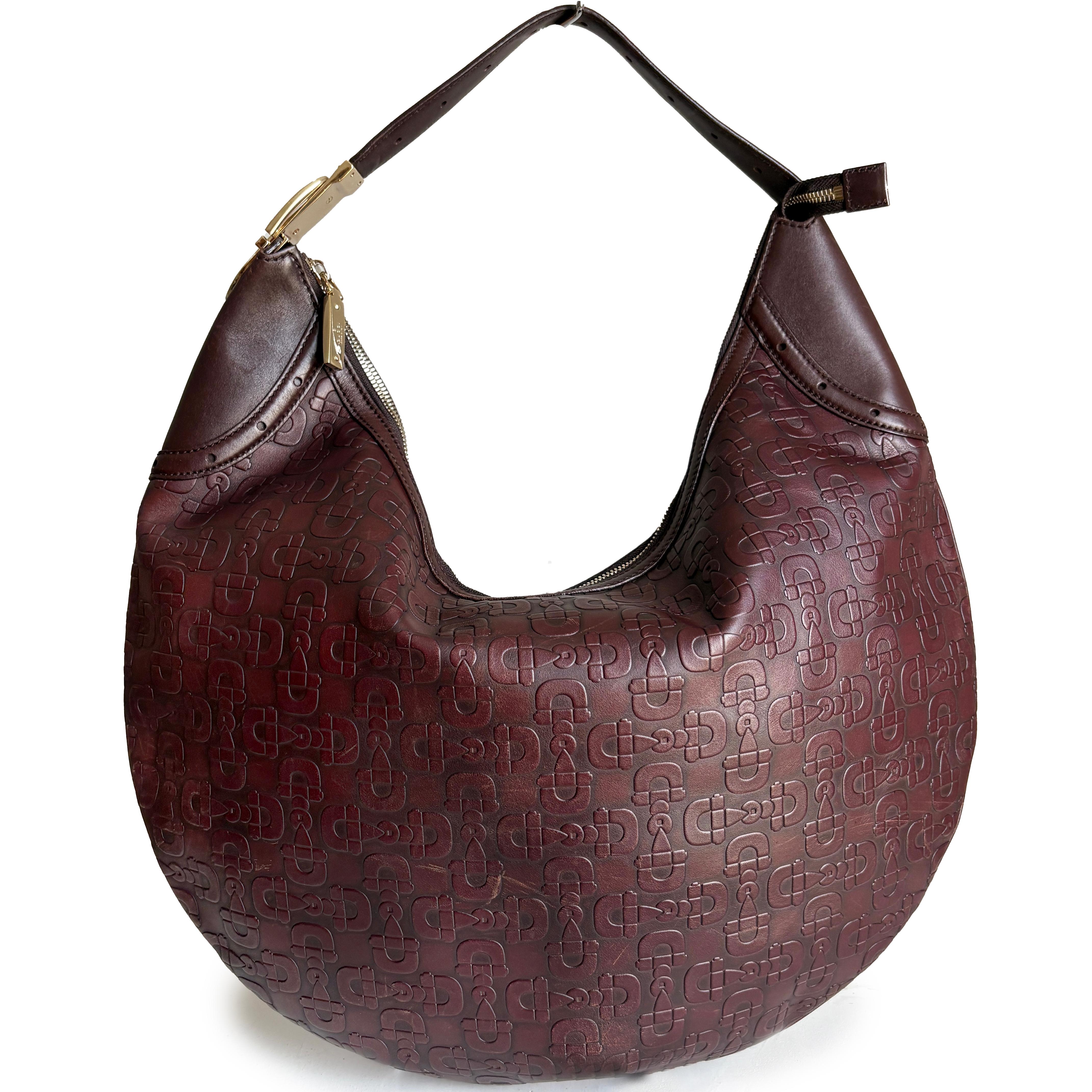 Gebrauchte Gucci Hobo-Tasche aus geprägtem Pferdeleder in einem satten Rotbraun mit burgunderroten Untertönen. Auf der Außenseite ist das ikonische Gucci-Pferdekopfmotiv eingeprägt, das der Tasche eine unverwechselbare, vom Pferdesport inspirierte