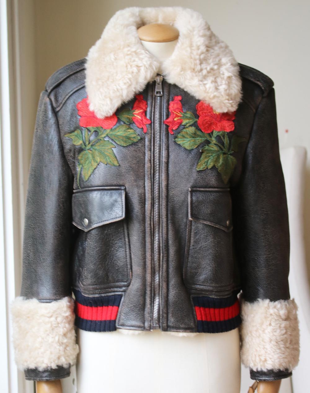 Gucci's shearling lined leather jacket is embroidered with decorative flowers at the chest and a bold LOVED slogan across the shoulders.
This cropped Gucci jacket features the label's signature red and blue Web trim finish.
Two front flap