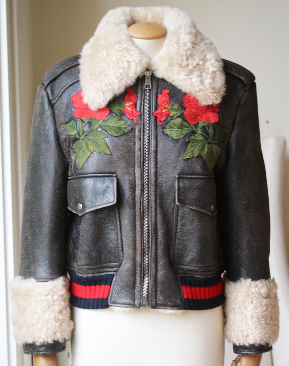 Gucci's shearling lined leather jacket is embroidered with decorative flowers at the chest and a bold LOVED slogan across the shoulders. This cropped Gucci jacket features the label's signature red and blue Web trim finish. Two front flap pockets.