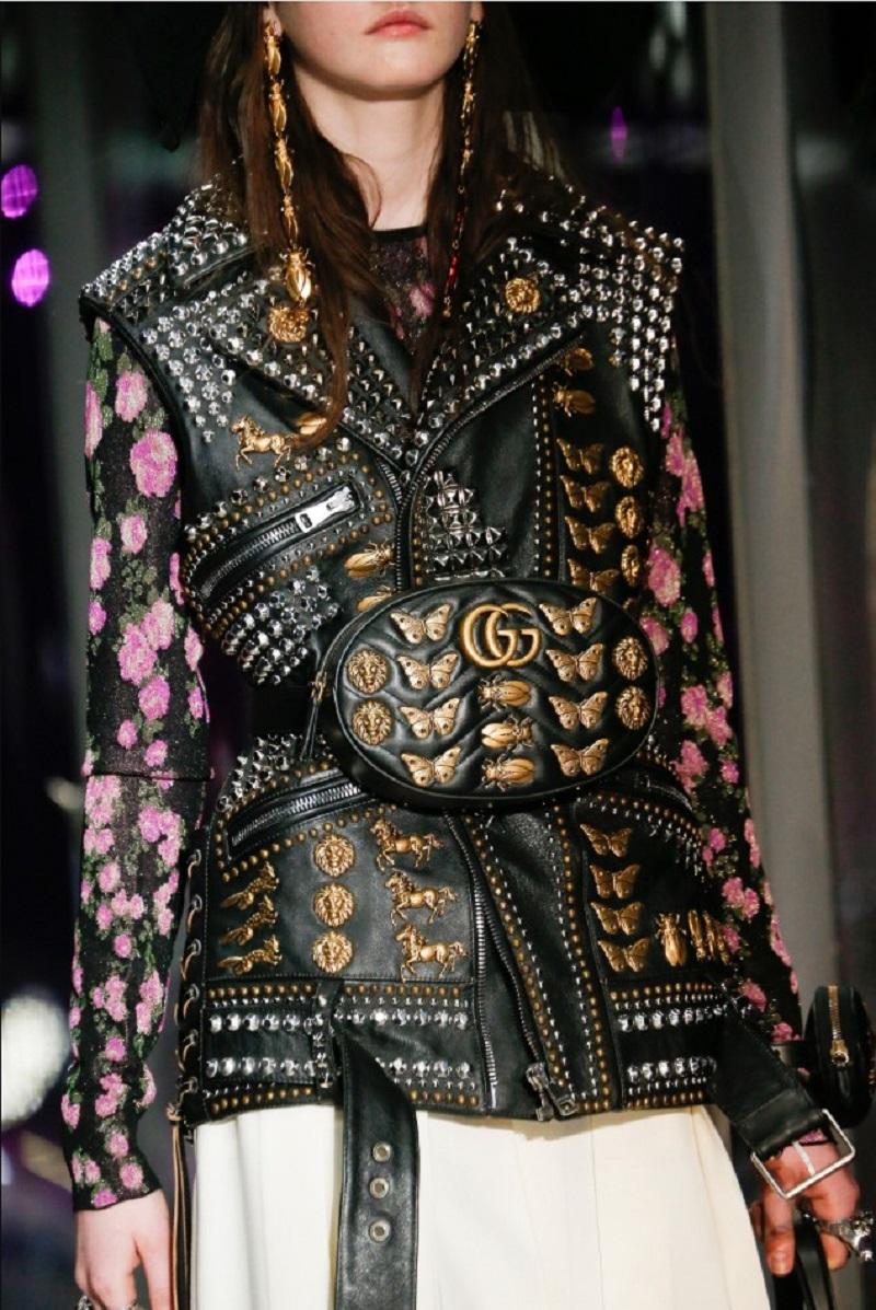 Realizzato in Italia, il gilet è una fusione magistrale di alta moda e ribellione rock. Realizzato in pelle di vitello nera, il gilet presenta un'esplosione di decorazioni metalliche - borchie a cono e a cupola color argento, rivetti e cerniere -
