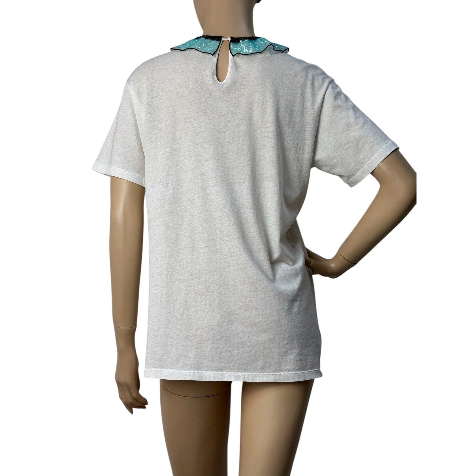 

La delicata T-shirt bianca con una corona di fiori ricamata e una scritta in francese evoca leggerezza e profondità emotiva. La caratteristica principale вЂ