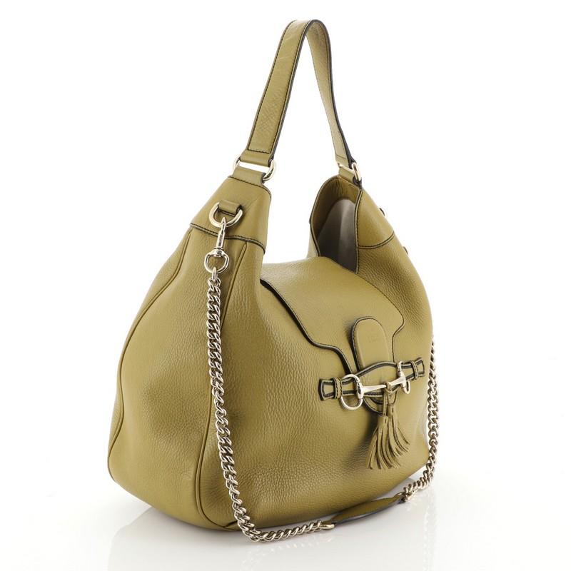 This Gucci Emily Hobo Leather Medium, crafted in green leather, features horsebit design with leather tassels at the front, looped leather strap, and gold-tone hardware. Its slide flap closure opens to a neutral fabric interior with side zip and