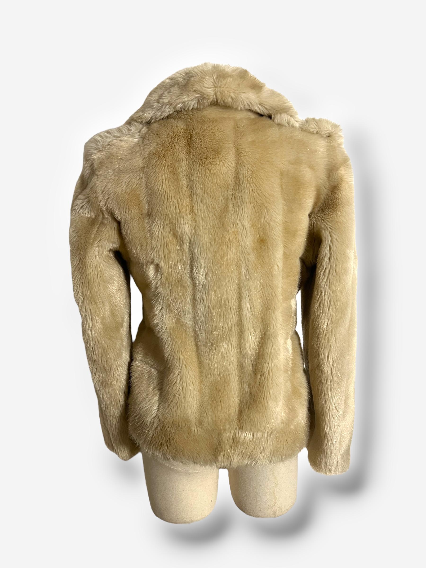 

Issu de la collection emblématique automne-hiver 1996 de Tom Ford pour Gucci, ce manteau en fausse fourrure pelucheuse incarne l'esthétique glamour et sensuelle de l'époque. Réalisé dans un ton crème doux, ce manteau est conçu dans une silhouette