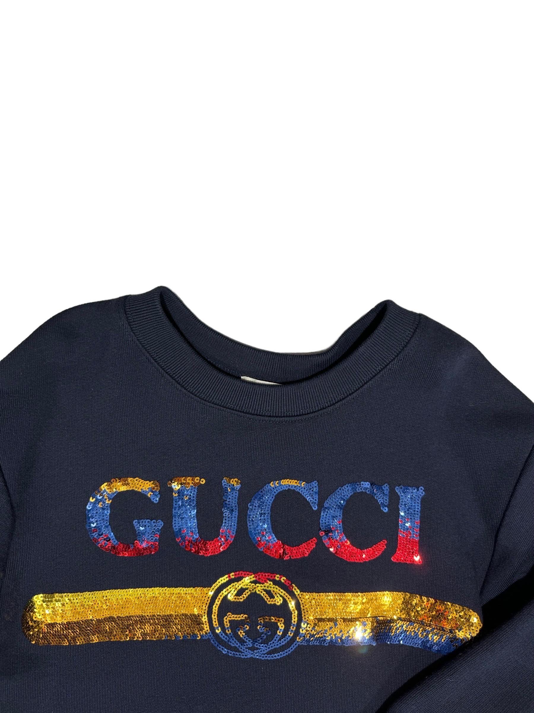 Felpa baby firmata Gucci, realizzata in cotone garzato di colore blu, sulla parte frontale presenta la scritta del brand in paillettes di colore giallo, blu e rosso. All’estremità dei polsi è realizzata in costine.

Taglia 4 anni. L’articolo si