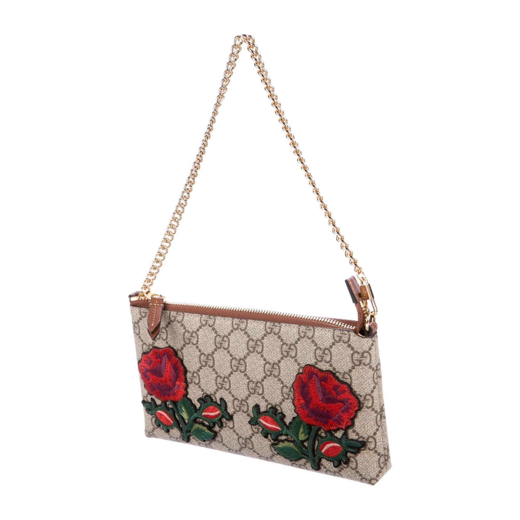 From the 2016 Collection. Brown and beige coated canvas Gucci GG Supreme pochette with gold-tone hardware, brown leather trim, crimson and multicolor floral embellishments at front, tan suede lining featuring single zip pocket at interior wall, six