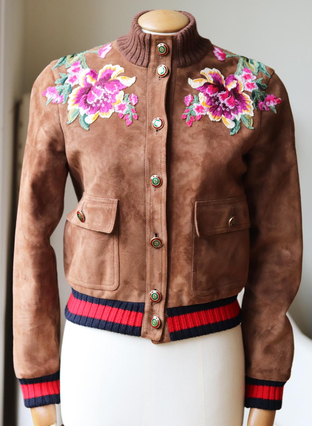 Cette veste Gucci est un véritable exemple de l'artisanat exceptionnel du label:: avec ses fleurs décoratives brodées de manière ludique sur la poitrine et un slogan LOVED audacieux sur les épaules. 
Confectionné en Italie en daim marron dans une