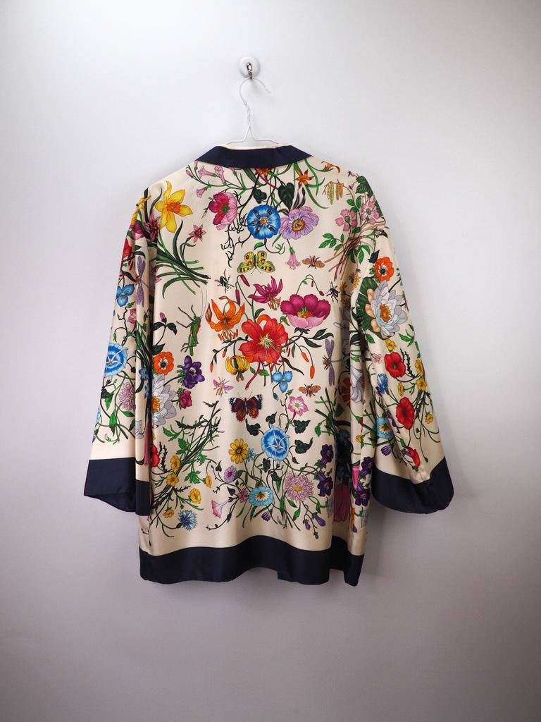 Gucci Floral Print Silk Foulard Shirt, with a 3/4 sleeve, floral pyjama-style blouse in cream, indigo, light-blue, red, orange, yellow, green, purple and pink silk (100%) with a v-neck. Closes in the front with a zipper and has front patch-pockets.