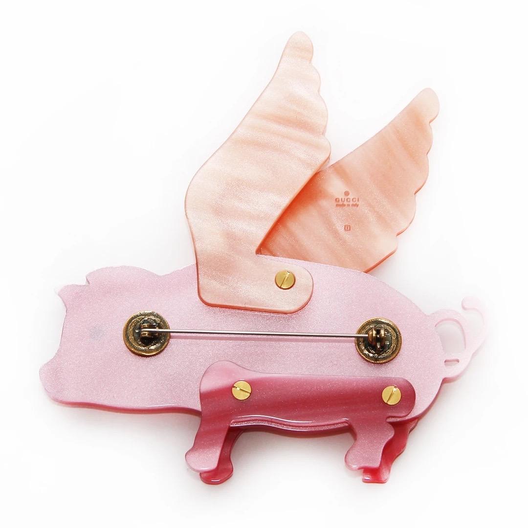 Gucci by Alessandro Michele Flying Pig Brooch 
Spring / Summer 2019 Collection 
Seen on Looks 46 and 47
Made in Italy 
Resin with mother of pearl effect 
Pink resin pig with peach resin wings 
Has black Gucci stamp on wings 
Antique gold tone metal