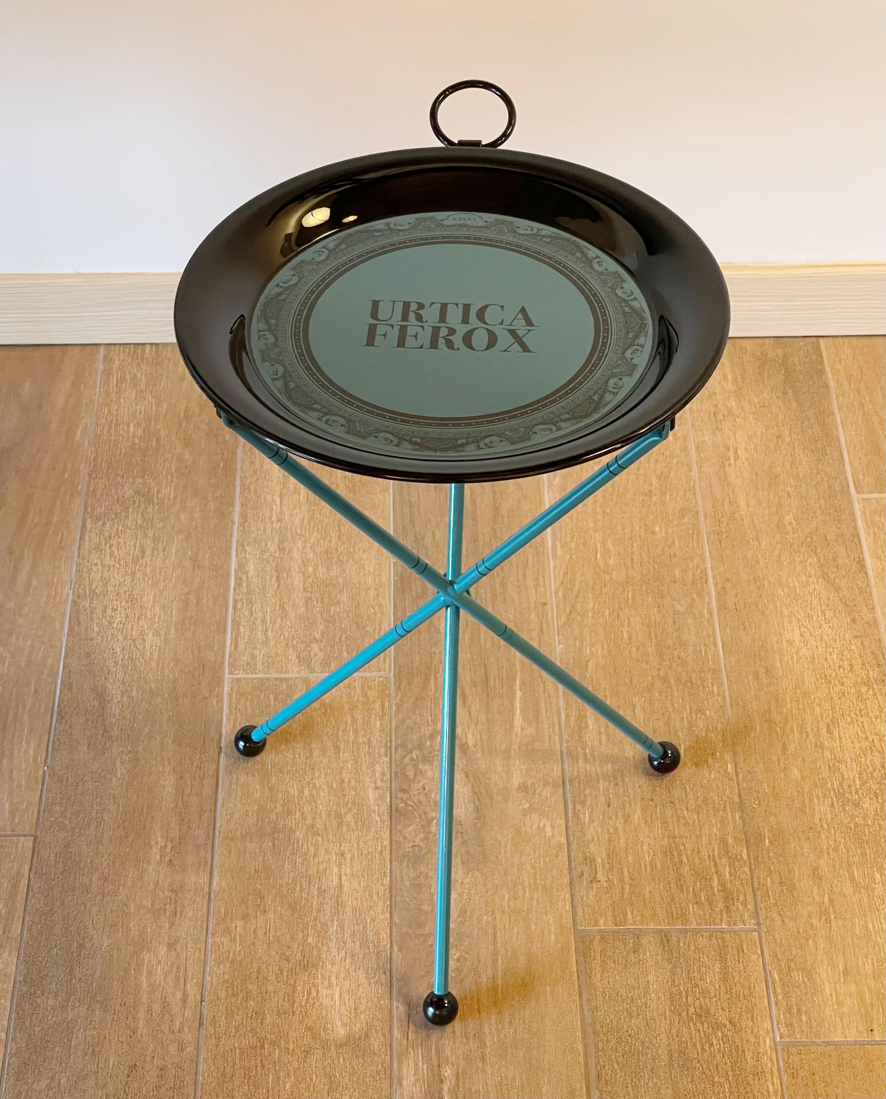 Gucci black and blue metal folding tray table which is set atop 3 legs and equipped with a ring at the top, with 