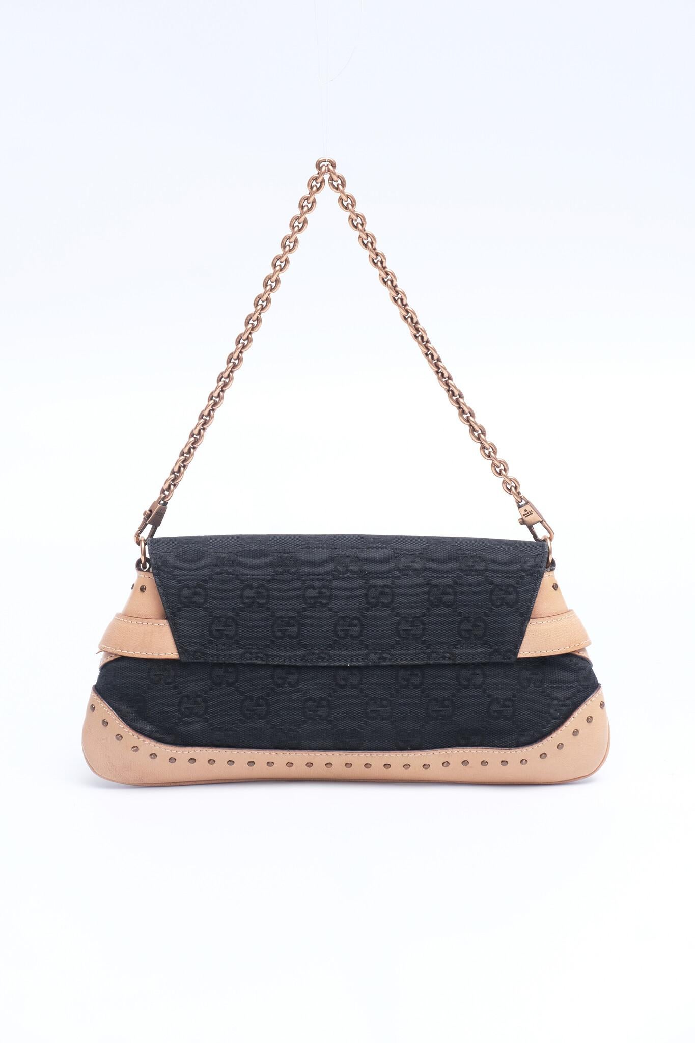 Authentic GUCCI Monogram Studded Horsebit Clutch in Black & Tan. Crafted from GG monogram canvas with a beige leather base and trim. Features a bronze horse-bit detail, studded borders, and a bronze chain strap. The flap opens to a black fabric