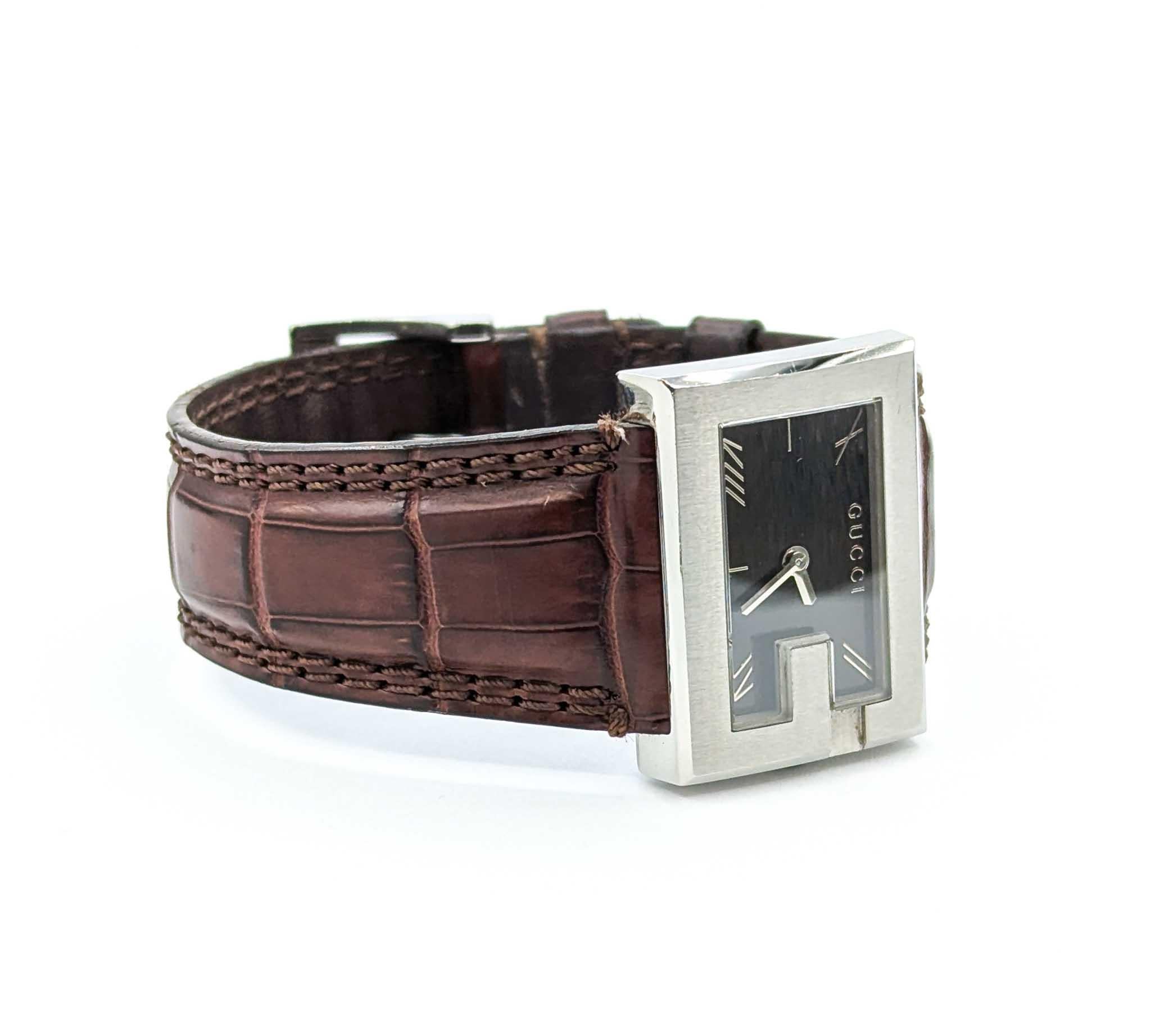 Este reloj de pulsera Gucci G 100L presenta una atrevida caja rectangular de acero inoxidable de 30x22 mm con el icónico diseño del bisel en 