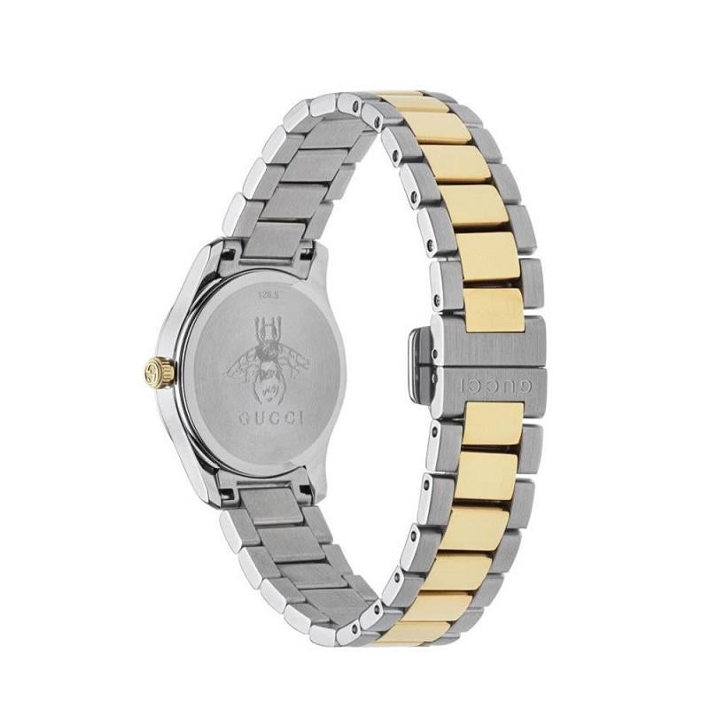 A chic two tone piece from Gucci. The Gucci Timeless watch has a round stainless steel case with a smooth polished bezel. The silver dial features a yellow tone cat head, and yellow hands. The indexes are set with diamonds with the Gucci logo at the