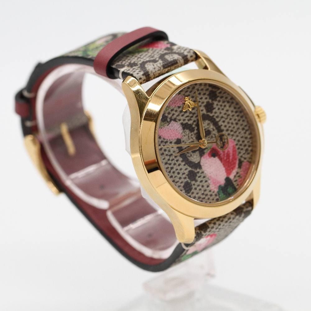 GUCCI G-TIMELESS PINK BLOOMS YA1264038 Brand New Watch, 38mm yellow gold plated stainless steel case excluding crown. Sapphire crystal. Floral print dial. Multicoloured leather strap. Quartz movement. Water resistant 5atm. Delivered with box.