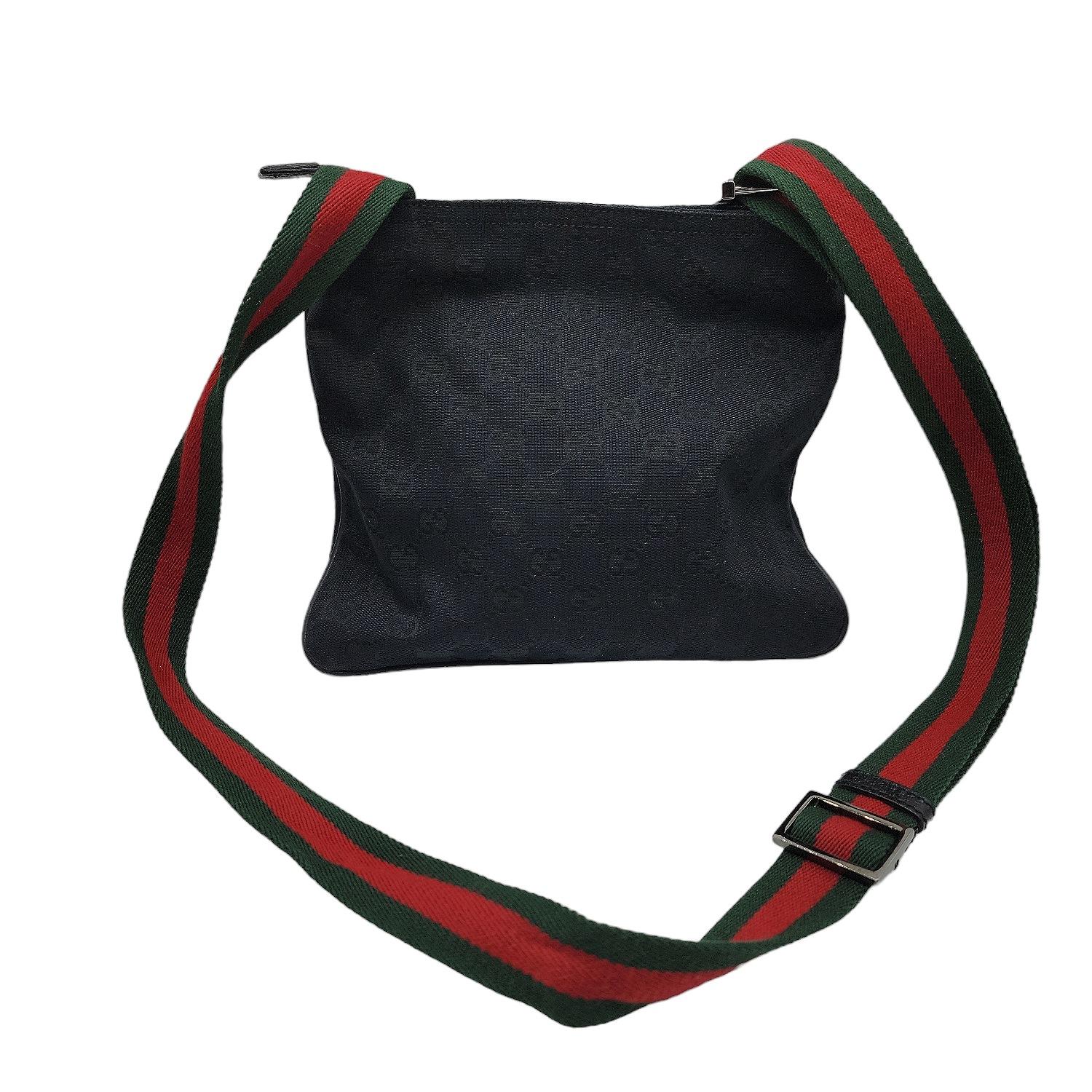 Black GG canvas Gucci small messenger bag with gunmetal hardware, single green and red Web-trimmed adjustable shoulder strap, debossed logo placard at front face, tonal leather trim and piping, tonal woven lining, single zip pocket at interior wall