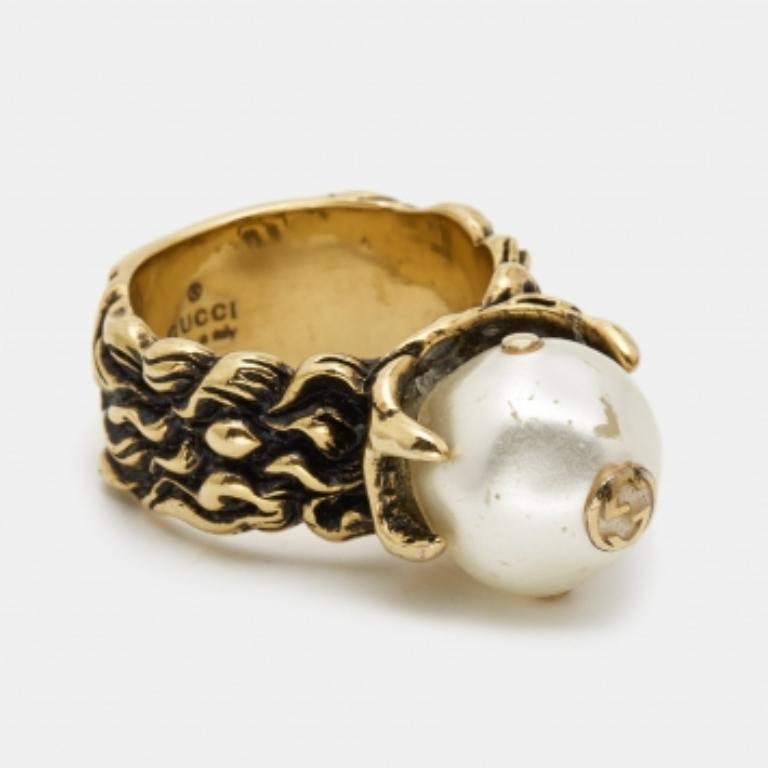Cette bague Gucci est réalisée en métal doré et rehaussée de perles. Nous voyons la beauté prendre vie dans cette création également.