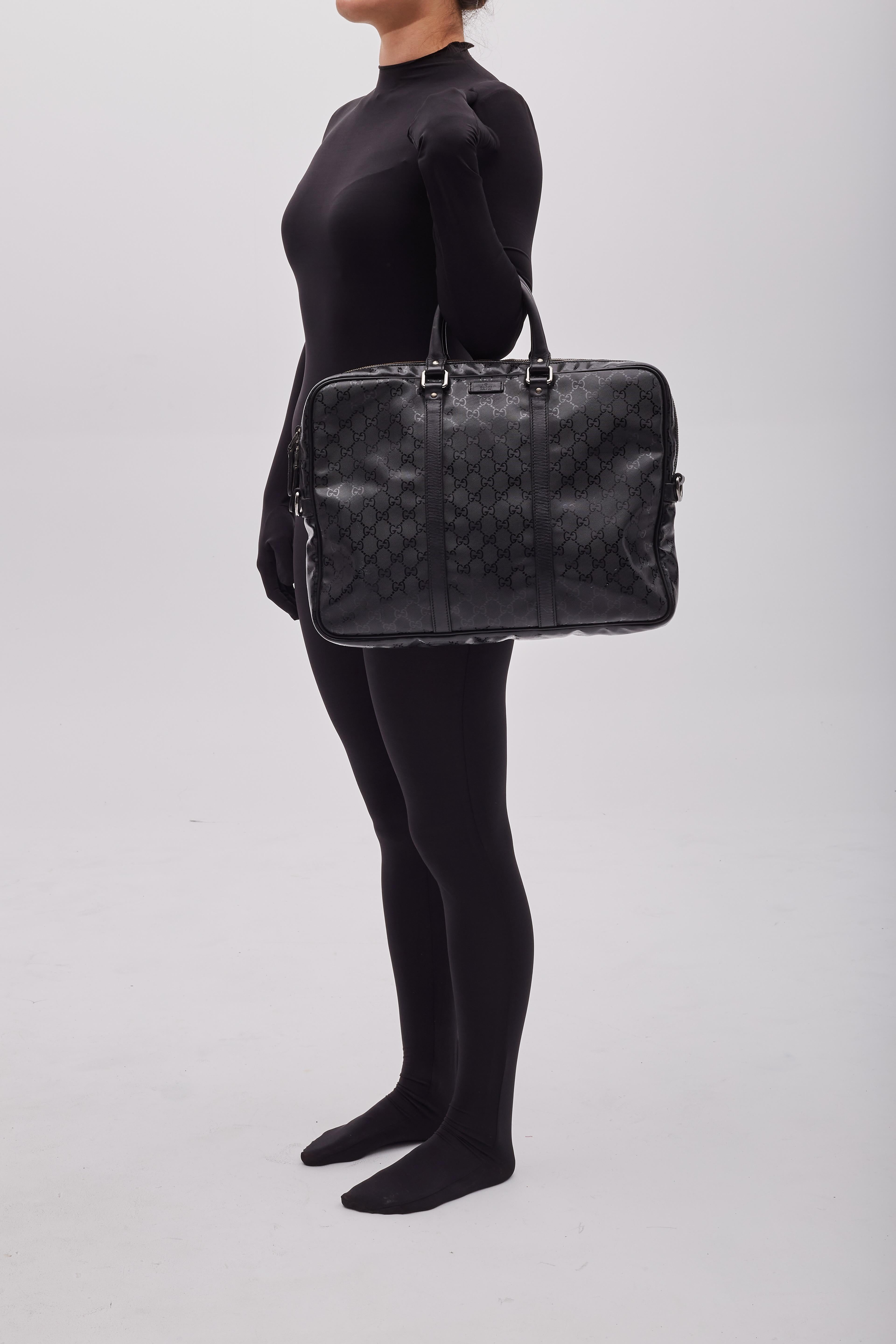 Diese Gucci Aktentasche zeichnet sich durch schwarzes, mit Monogrammen beschichtetes Segeltuch, Lederdetails, zwei gerollte Ledergriffe, einen Reißverschluss mit doppelter Lasche, silberfarbene Beschläge und ein schwarzes Segeltuchfutter mit Taschen