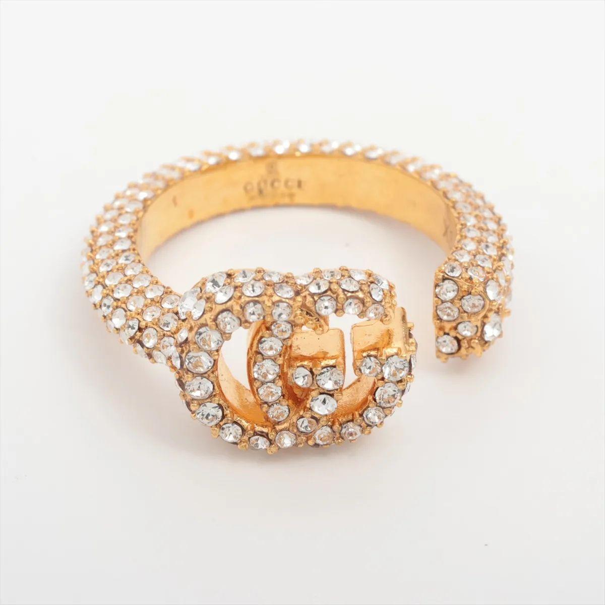 L'anello con logo GG di Gucci con strass è un pezzo di grande effetto che mette in mostra il glamour e la maestria del marchio. Caratterizzato dall'iconico logo GG, l'anello è completamente incrostato di strass scintillanti che catturano la luce da