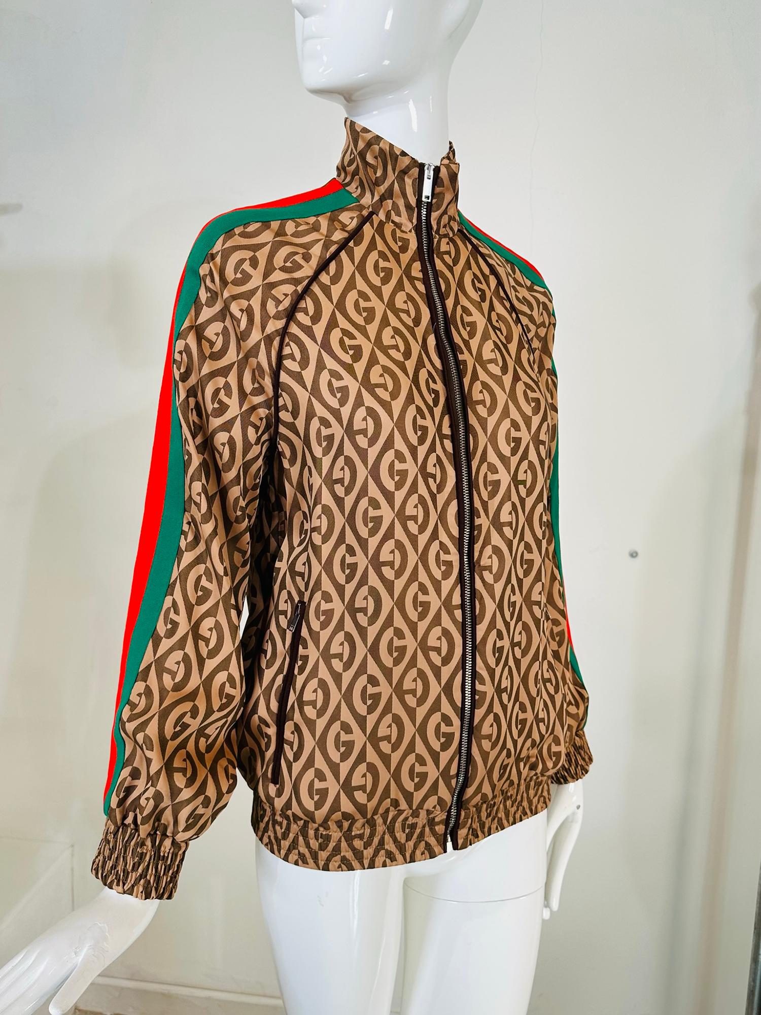 Brown GG print bomber jacket from Gucci. Unworn with tag. Featuring a front zip fastening, front zippered pockets. a stand up collar, long sleeves, with cased elastic cuffs and cased elastic hem. Relaxed fit. Raglan sleeves with signature green &
