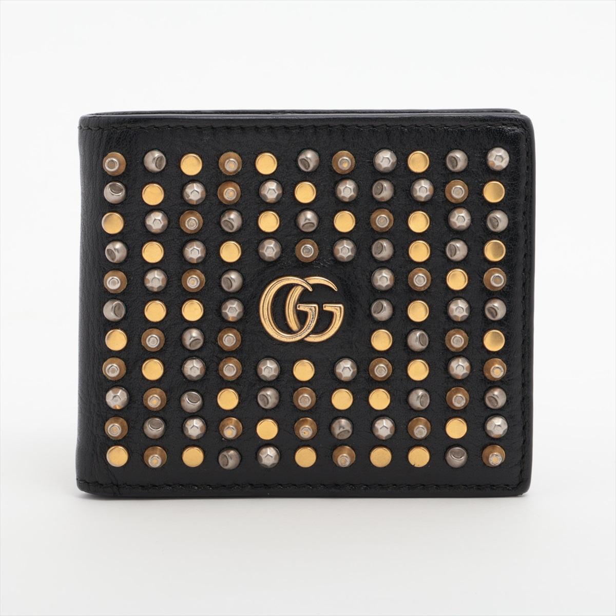 The Gucci GG Logo Studs Leather Compact Wallet in black is a stylish and compact accessory that embodies the brand’s timeless elegance. Crafted from premium black leather, the wallet is adorned with a mix of gold, brown, and nude-tone studs,