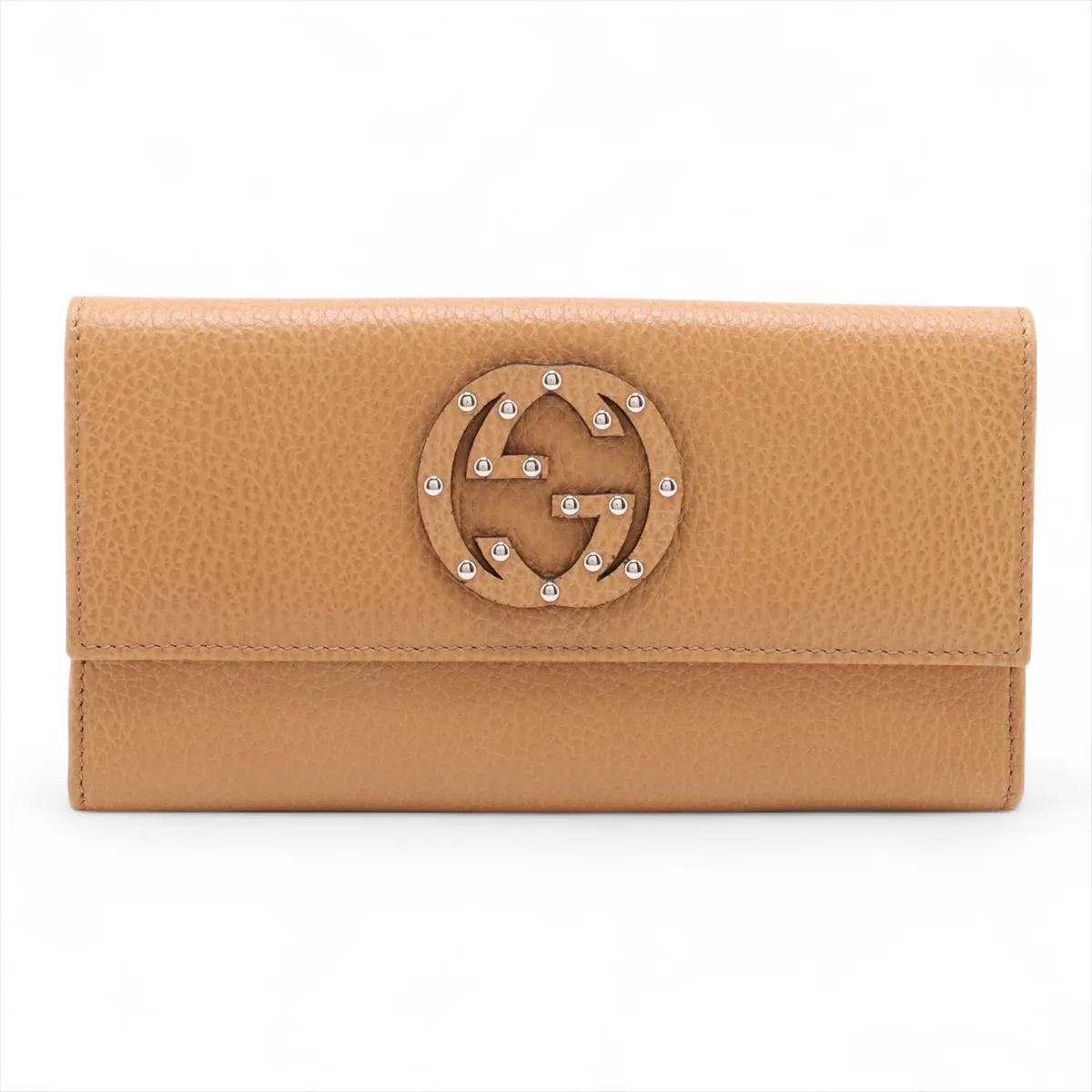 Il portafoglio lungo in pelle GG Logo Sukey di Gucci in marrone chiaro è un accessorio sofisticato che combina eleganza e funzionalità quotidiana. Realizzata in pelle di alta qualità, presenta l'iconico logo GG con borchie sul davanti, aggiungendo