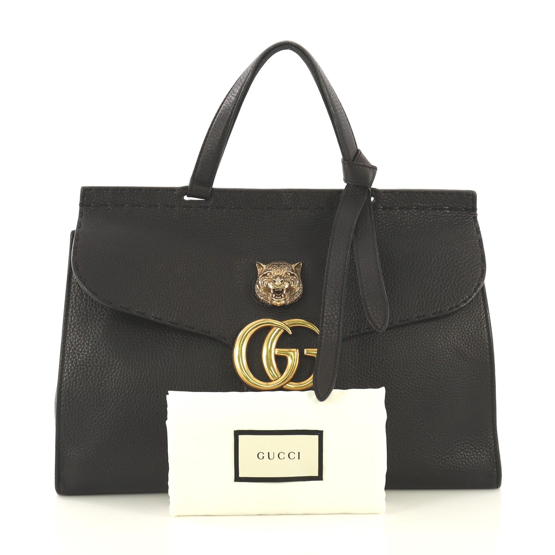 This Gucci GG Marmont Animalier Top Handle Bag Leather Medium, crafted from black leather, features flat top handle with knot on one end, flap with GG logo and animalier detail on top, stitching detail, and aged gold-tone hardware. Its push-lock
