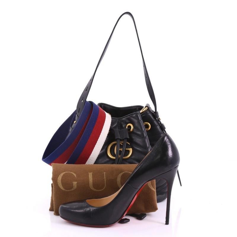 This Gucci GG Marmont Bucket Bag Matelasse Leather Small, crafted in black matelasse leather, features an adjustable shoulder strap and gold-tone hardware. Its drawstring closure opens to a nude microfiber interior with slip pockets. **Note: Shoe