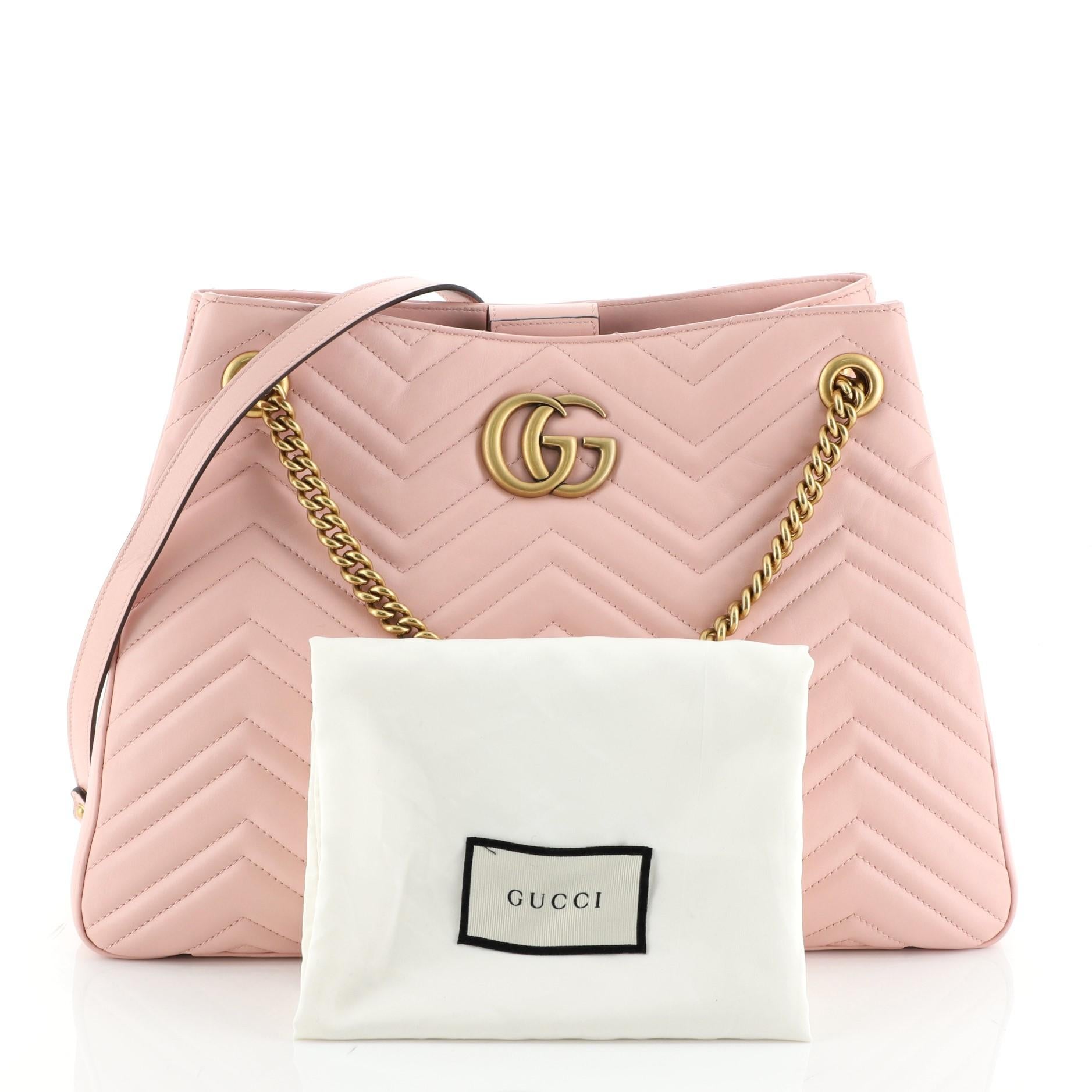 This Gucci GG Marmont Chain Shoulder Bag Matelasse Leather, crafted from pink matelasse leather, features chain strap with leather pad, interlocking GG logo, and matte gold-tone hardware. Its hidden magnetic snap closure opens to a gray microfiber