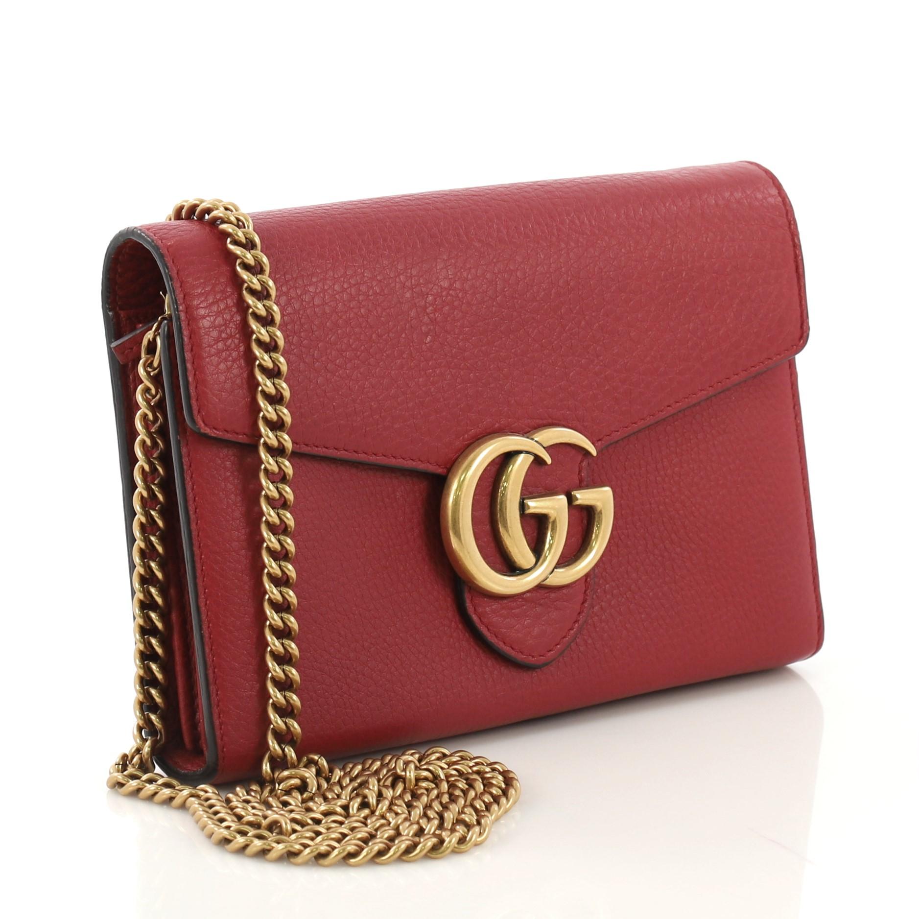 This Gucci GG Marmont Chain Wallet Leather Mini, crafted from red leather, features chain-link shoulder strap, interlocking GG logo, and aged gold-tone hardware. Its snap closure opens to a black fabric and red leather interior with multiple card