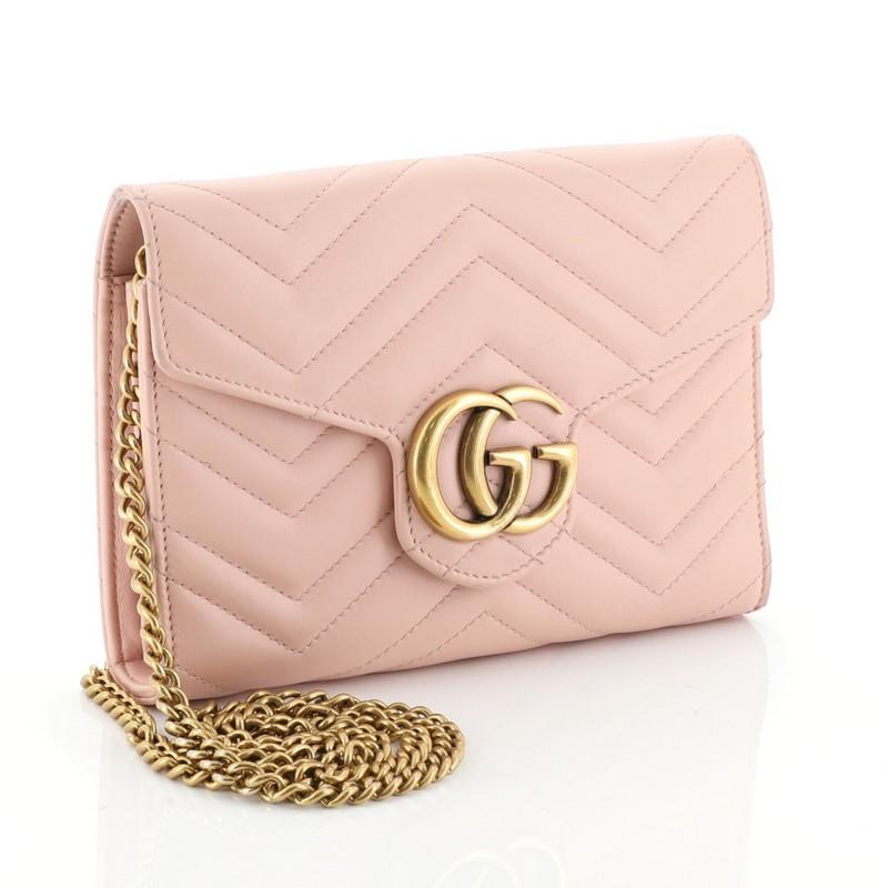 This Gucci GG Marmont Chain Wallet Matelasse Leather Mini, crafted from pink matelasse leather, features interlocking GG logo, chain link shoulder strap, and aged gold-tone hardware. Its snap closure opens to a pink leather and black microfiber