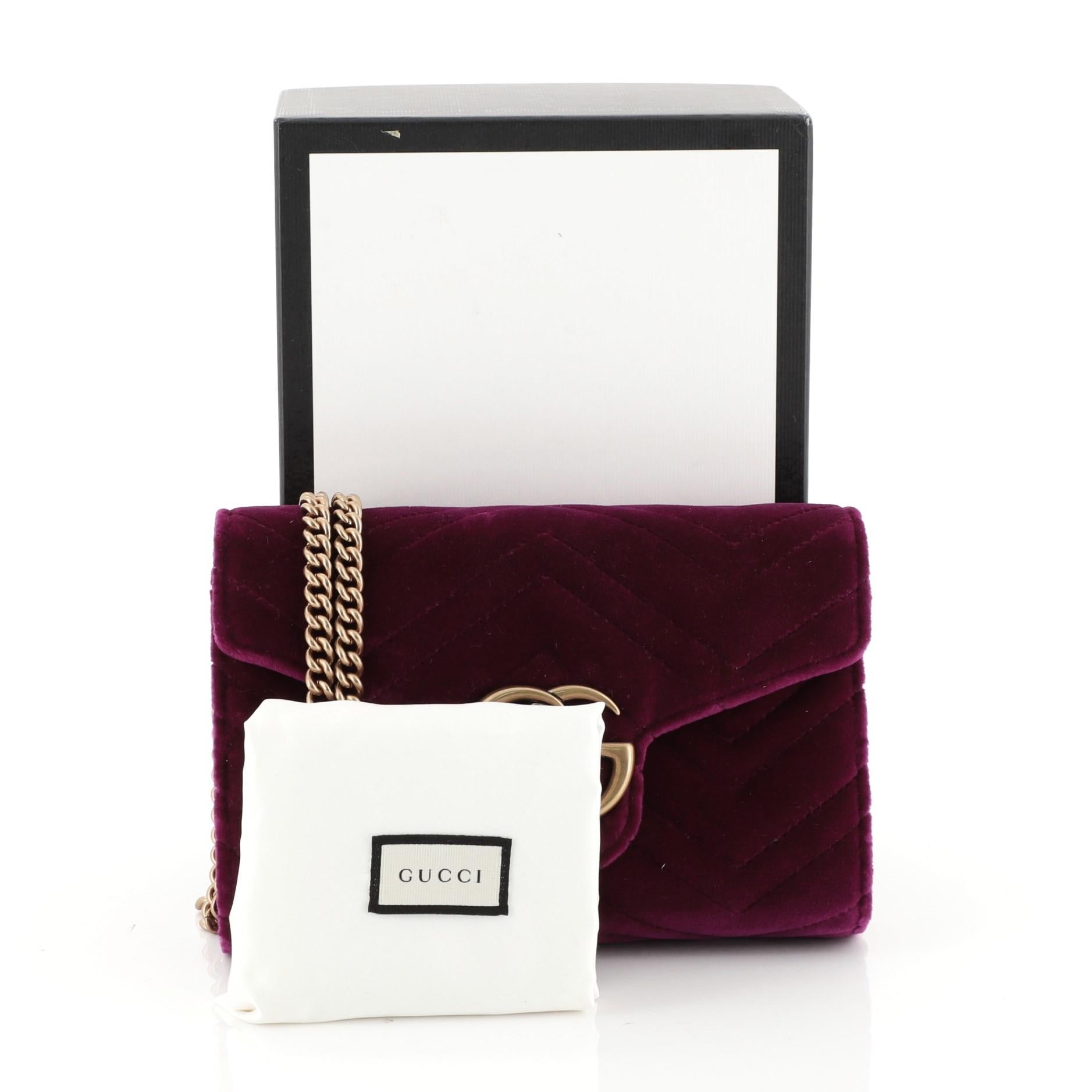 This Gucci GG Marmont Chain Wallet Matelasse Velvet Mini, crafted from purple matelasse velvet, features interlocking GG logo, chain link shoulder strap, and aged gold-tone hardware. Its snap closure opens to a purple leather and black nylon