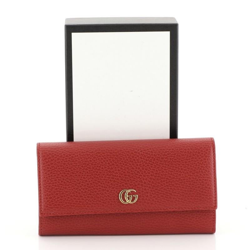This Gucci GG Marmont Continental Wallet Leather Long, crafted from red leather, features interlocking GG logo and gold-tone hardware. Its snap button closure opens to a red leather and black fabric interior with middle zip pocket, slip pockets and