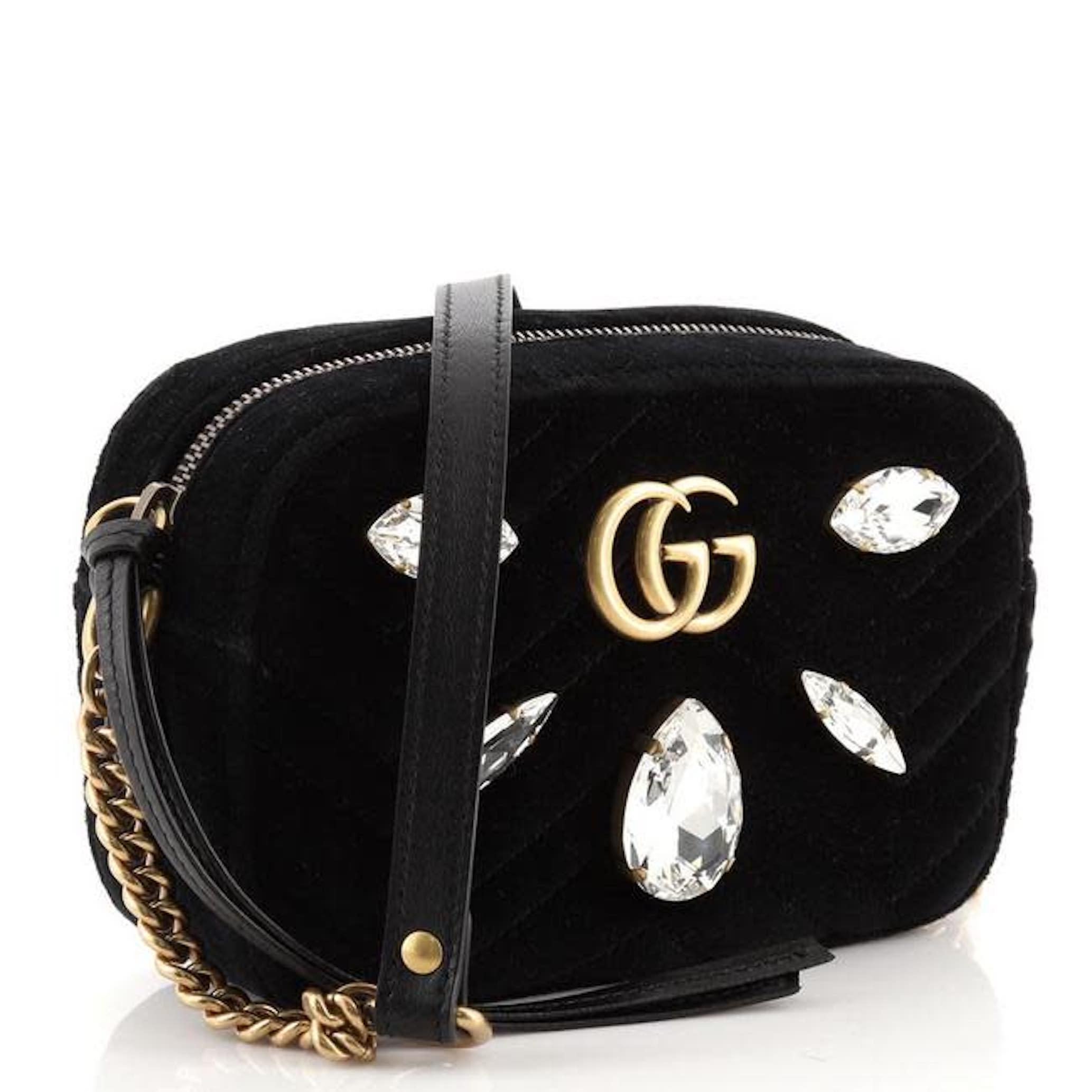 This Gucci shoulder bag is crafted of soft velvet in black. It features an aged gold chain, a chain link and leather shoulder strap. The front features an interlocking aged gold GG logo and bold marquise crystals. The bag opens to a pink satin
