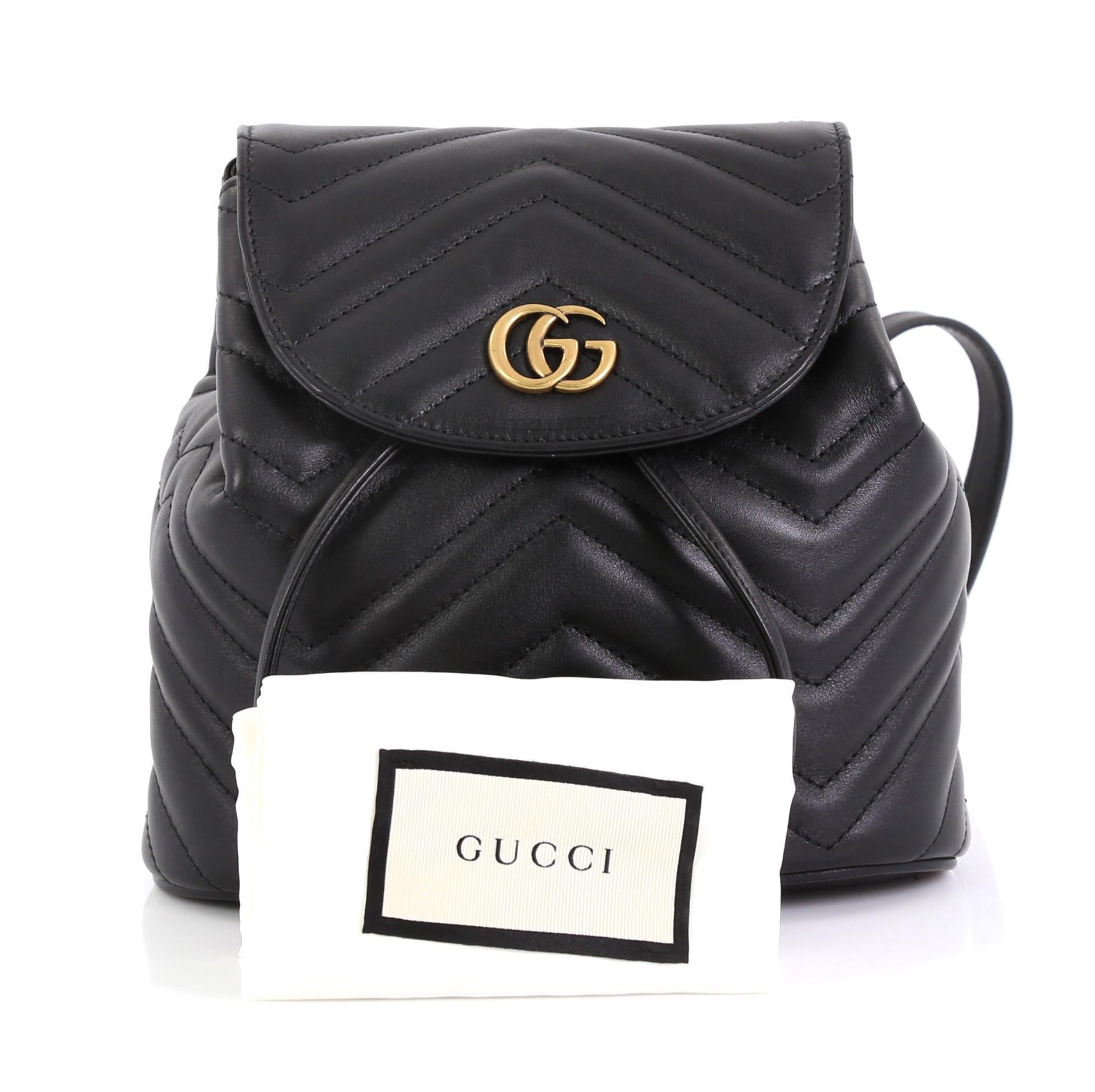 This Gucci GG Marmont Drawstring Backpack Matelasse Leather Mini, crafted from black matelasse leather, features dual leather straps with chain, interlocking GG logo on its flap, and aged gold-tone hardware. Its drawstring closure opens to a neutral