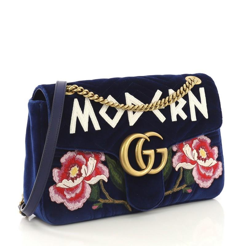 This Gucci GG Marmont Flap Bag Embroidered Matelasse Velvet Medium, crafted in blue matelasse velvet, features chain link shoulder strap with leather pad, embroidered flowers and the word 'modern', GG logo at front flap, and aged gold-tone hardware.