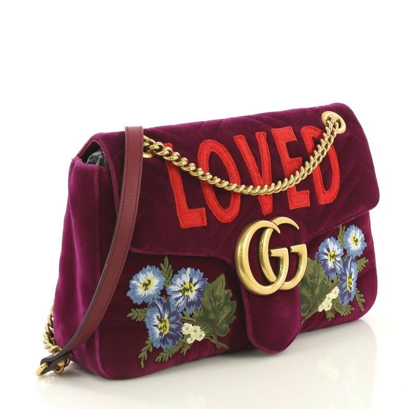 This Gucci GG Marmont Flap Bag Embroidered Matelasse Velvet Medium, crafted in purple matelasse velvet, features chain link shoulder strap with leather pad, embroidery, GG logo, and aged gold-tone hardware. Its push-lock closure opens to a pink