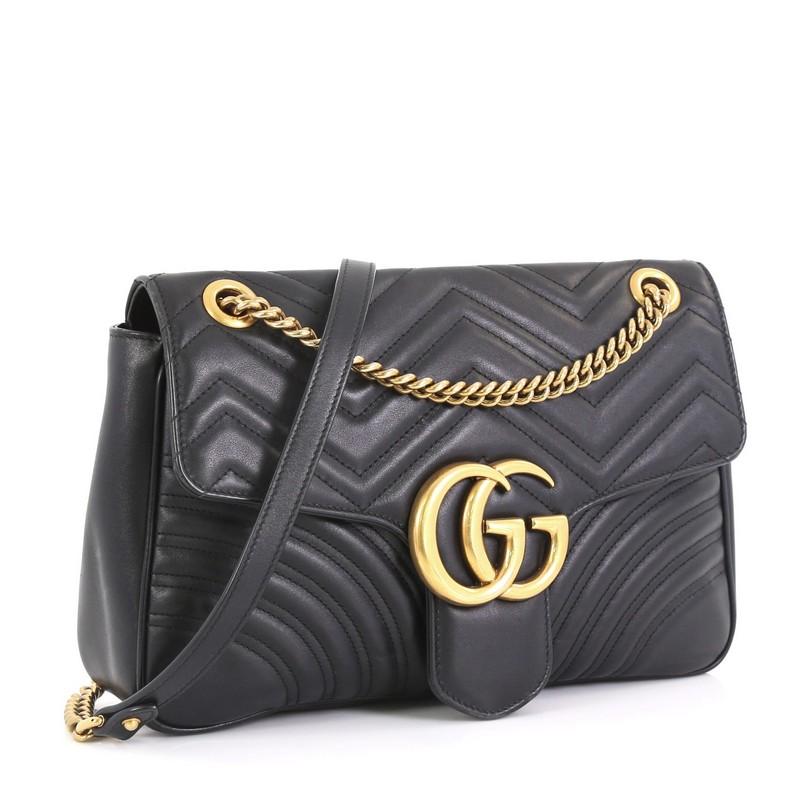 This Gucci GG Marmont Flap Bag Matelasse Leather Medium, crafted from black matelasse leather, features chain link strap with leather pad, flap top with GG logo, and aged gold-tone hardware. Its push-lock closure opens to a neutral microfiber