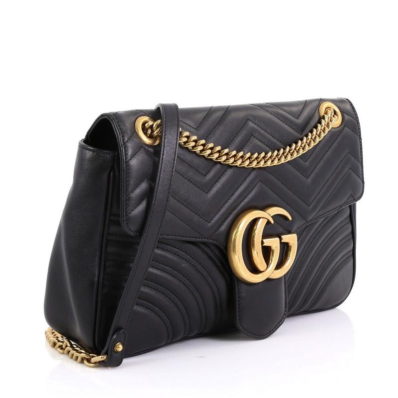 This Gucci GG Marmont Flap Bag Matelasse Leather Medium, crafted from black matelasse leather, features a chain link strap with leather pad, flap top with GG logo, and aged gold-tone hardware. Its push-lock closure opens to a nude microfiber