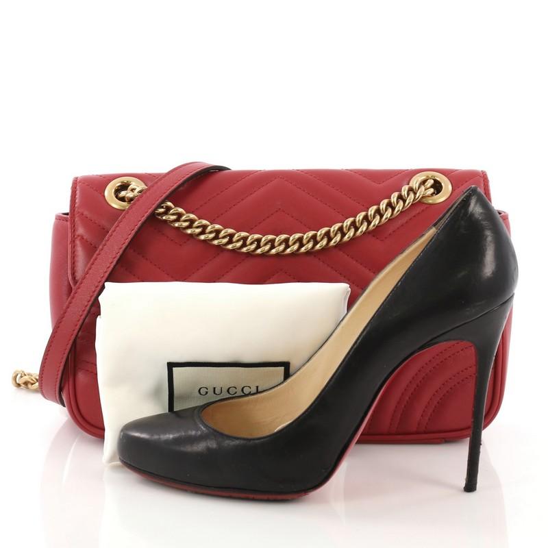 This Gucci GG Marmont Flap Bag Matelasse Leather Small, crafted from red matelasse leather, features a chain link strap with leather pad, flap top with GG logo, and aged gold-tone hardware. Its push-lock closure opens to a beige microfiber interior