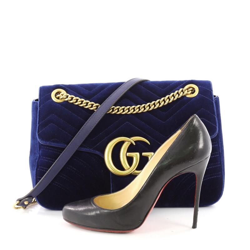 This Gucci GG Marmont Flap Bag Matelasse Velvet Medium, crafted from blue matelasse velvet, features chain-link shoulder strap with leather pad, flap top with GG logo and aged gold-tone hardware. Its push-lock closure opens to a pink satin interior