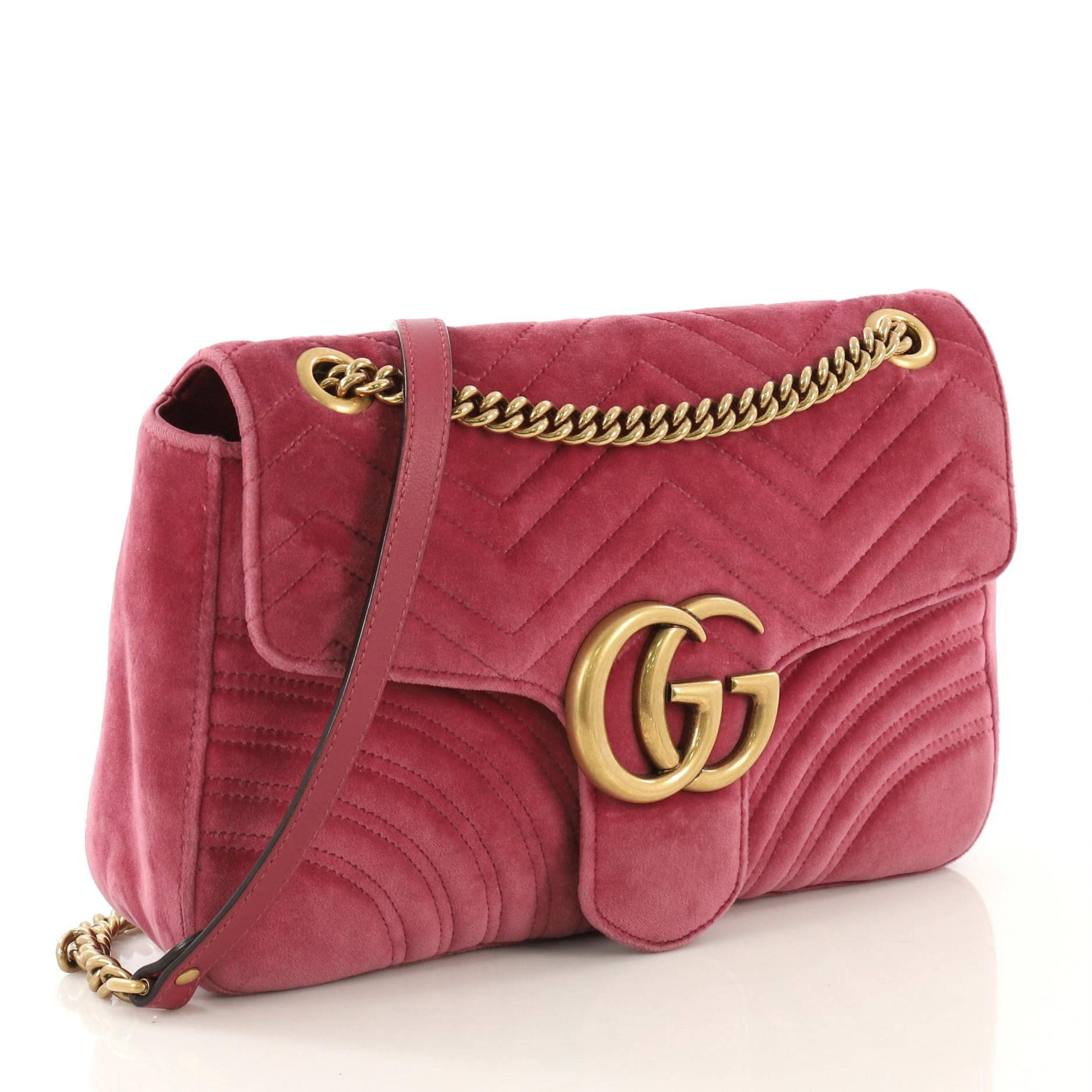 This Gucci GG Marmont Flap Bag Matelasse Velvet Medium, crafted from pink matelasse velvet, features a chain link strap with leather pad, flap top with GG logo, and aged gold-tone hardware. Its push-lock closure opens to a blue satin interior with