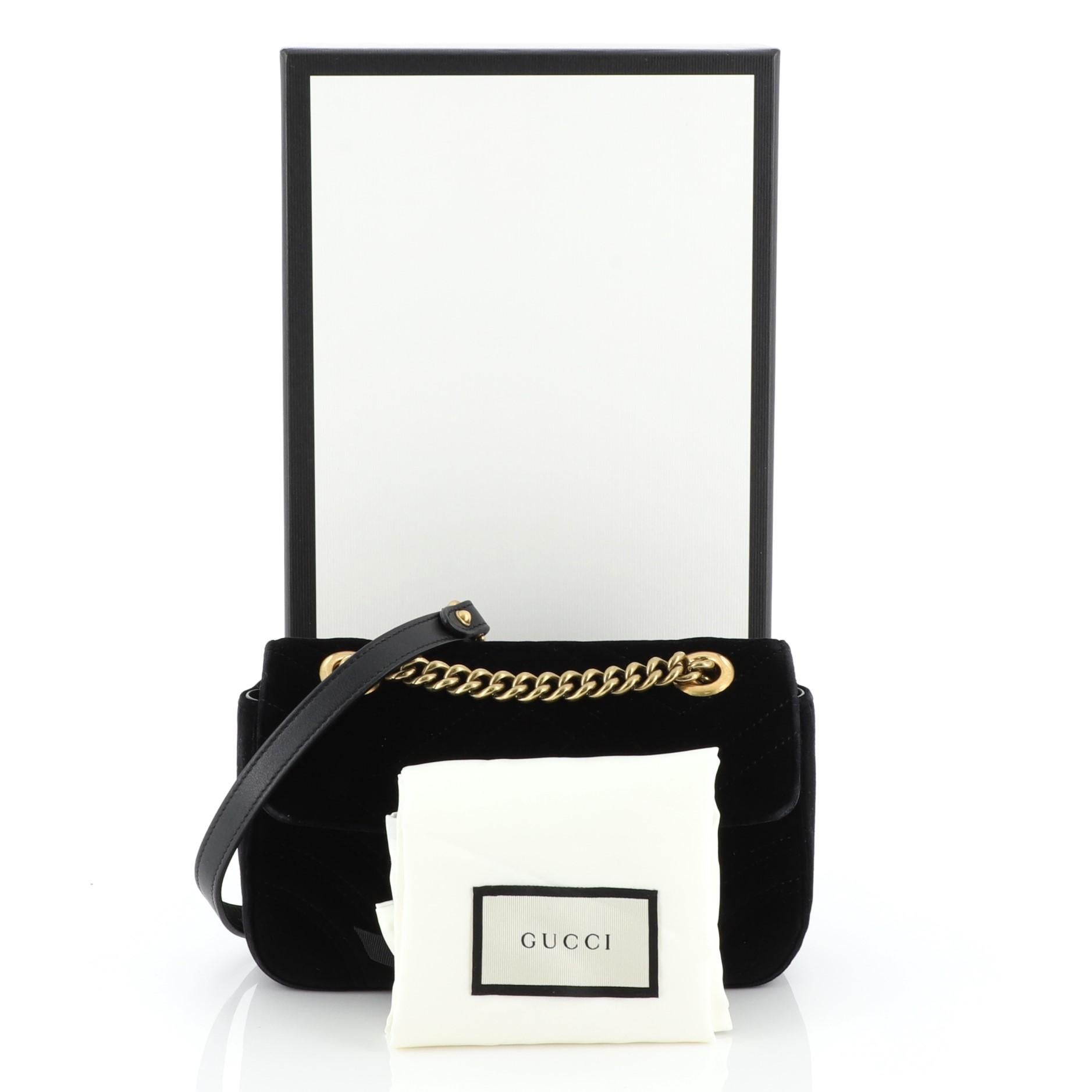 This Gucci GG Marmont Flap Bag Matelasse Velvet Small, crafted from black matelasse velvet, features chain link strap with leather pad, flap top with GG logo, and aged gold-tone hardware. Its push-lock closure opens to a pink satin interior with