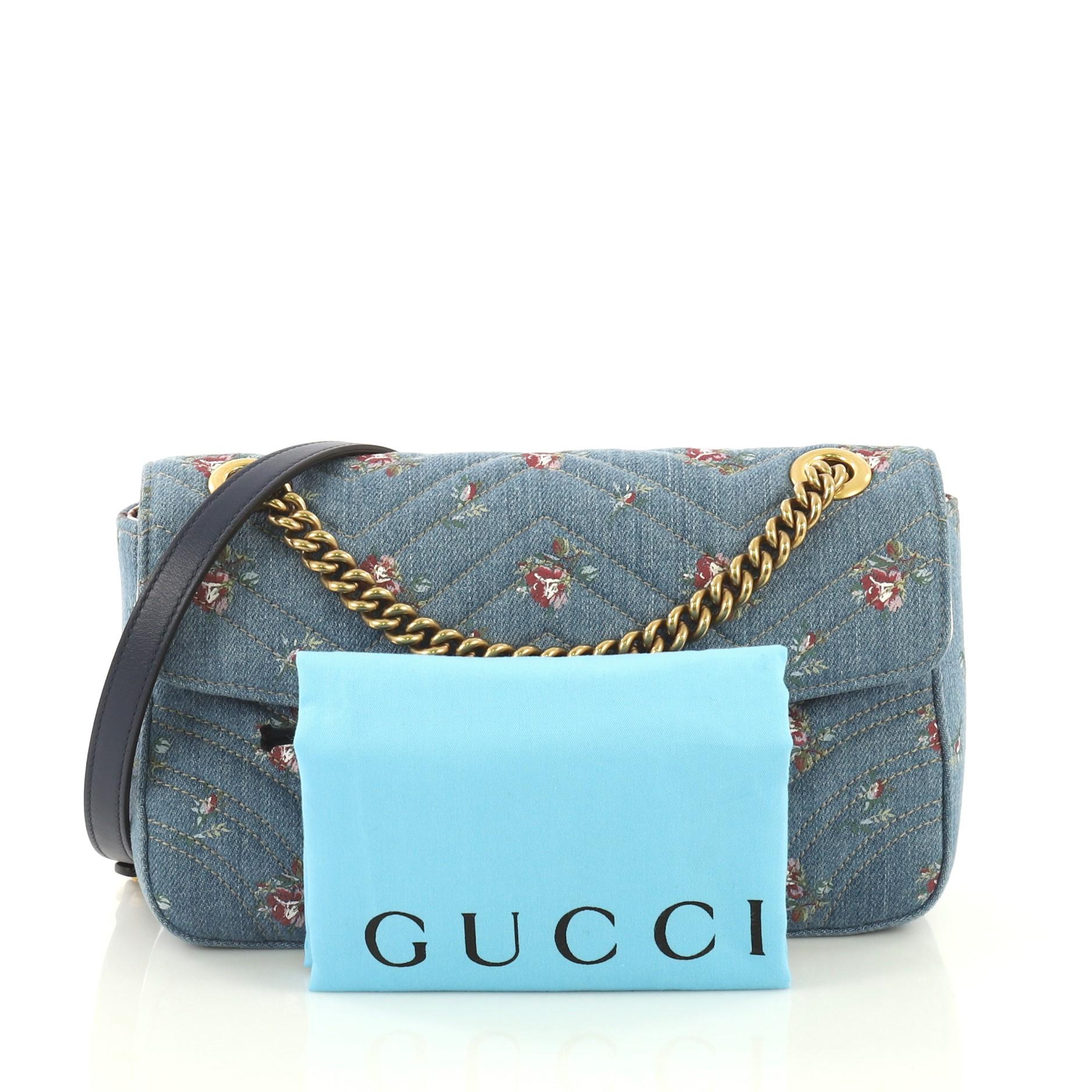 This Gucci GG Marmont Flap Bag Printed Matelasse Denim Small, crafted from blue printed matelasse denim, features a sliding chain strap with shoulder pad, flap top with interlocking GG logo, and gold-tone hardware. Its spring closure opens to a pink