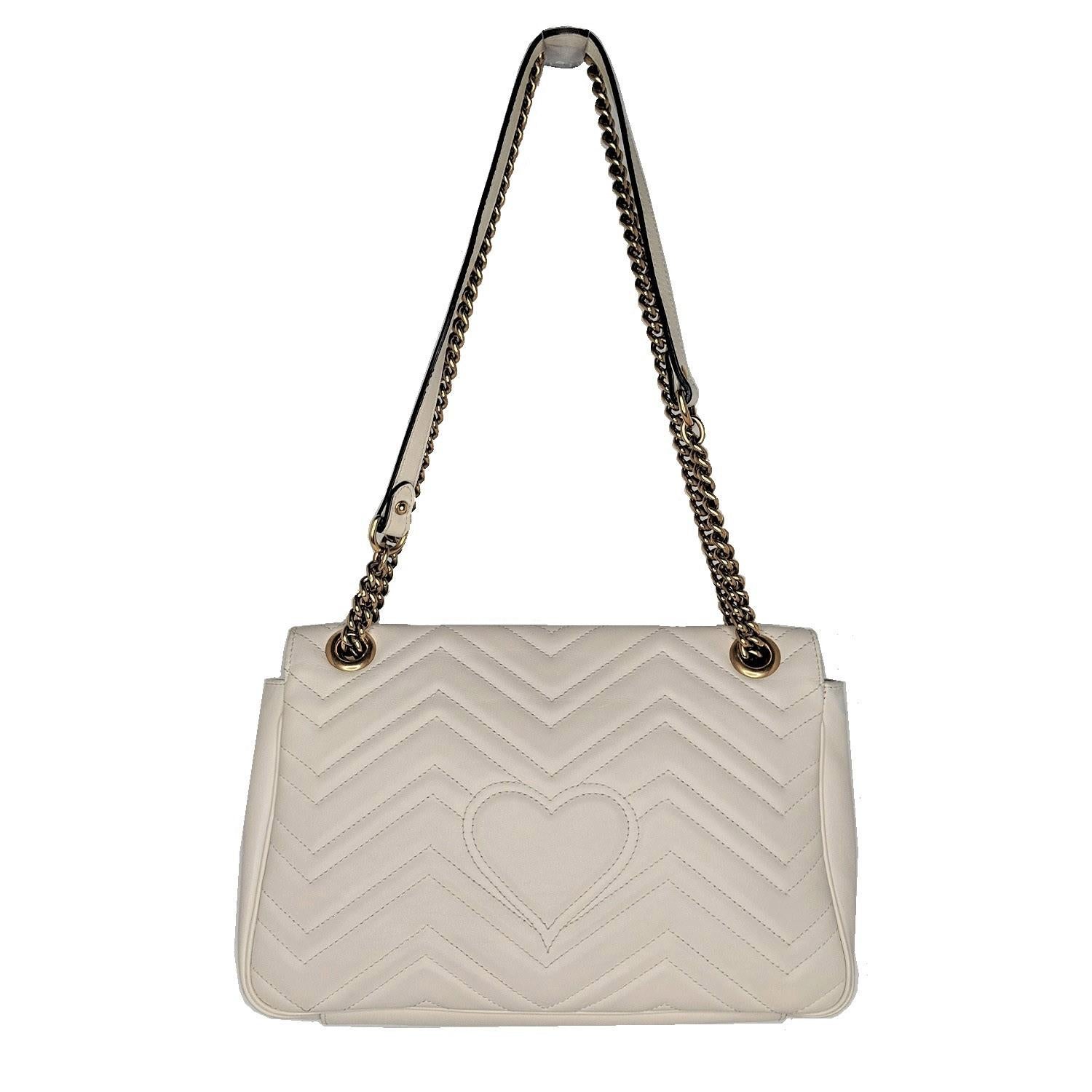 White Matelassé leather Gucci Large GG Marmont crossbody bag with antiqued gold-tone hardware, single convertible chain-link shoulder strap with leather shoulder guard, peach suede lining, three interior pockets; one with zip closure and push-lock