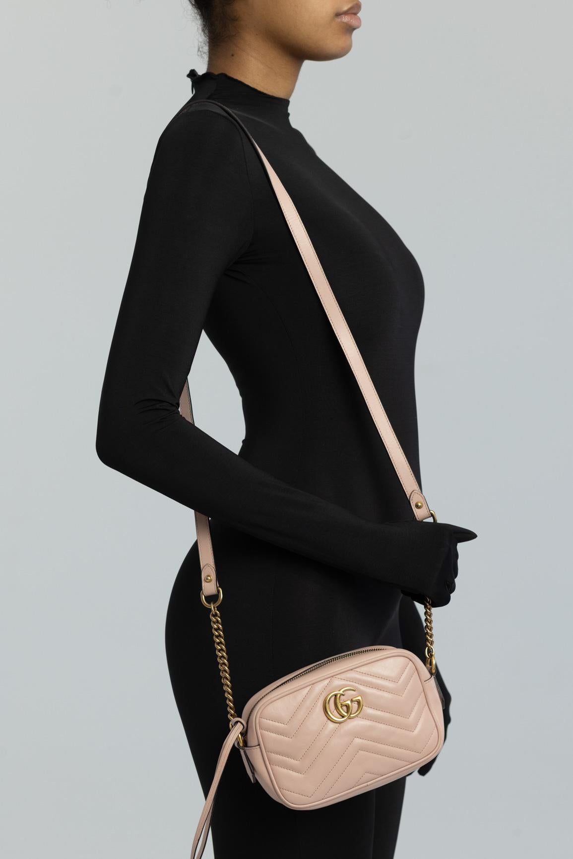 The mini GG Marmont chain shoulder bag has a softly structured shape and a zip top closure with Double G hardware. The chain strap has a leather shoulder detail. The camera bag is made in matelassé leather with a chevron design and GG on the