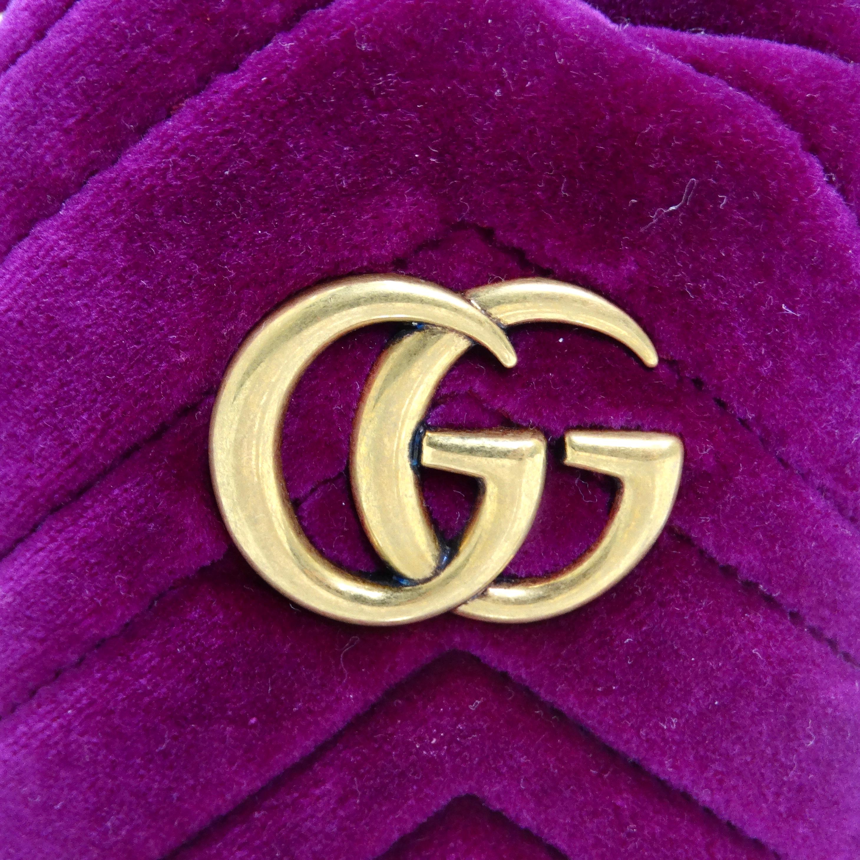Voici le mini sac à dos en velours GG Marmont de Gucci, un accessoire luxueux et stylé qui respire la sophistication et l'élégance. Confectionné en velours doux dans une riche teinte violet framboise, ce sac à bandoulière est une pièce d'apparat qui