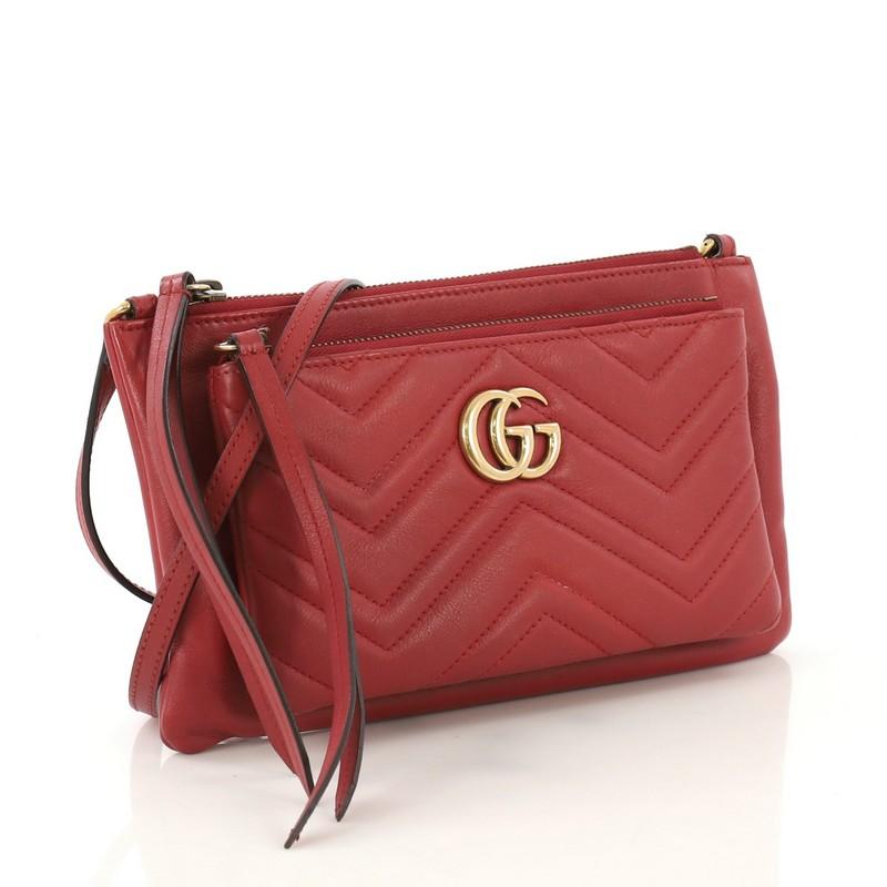This Gucci GG Marmont Pochette Crossbody Matelasse Leather Small, crafted in red matelasse leather, features an adjustable leather strap, exterior front zip pocket and aged gold-tone hardware. Its zip closure opens to a pink microfiber interior.