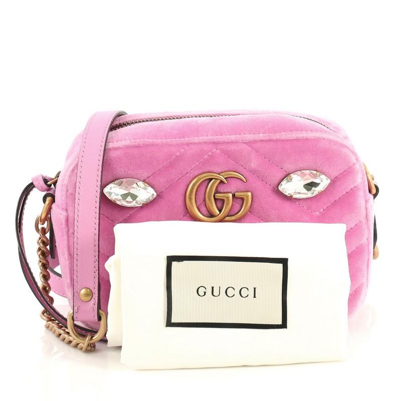 This Gucci GG Marmont Shoulder Bag Crystal Embellished Matelasse Velvet Mini, crafted from pink matelasse velvet, features leather shoulder strap with chain, GG logo and crystal embellishments, and aged gold-tone hardware. Its zip closure opens to a