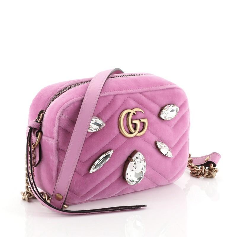 This Gucci GG Marmont Shoulder Bag Crystal Embellished Matelasse Velvet Mini, crafted from pink matelasse velvet, features leather shoulder strap with chain, GG logo and crystal embellishments, and gold-tone hardware. Its zip closure opens to a blue